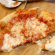 A cheese pizza cut into slices on a wood cutting board